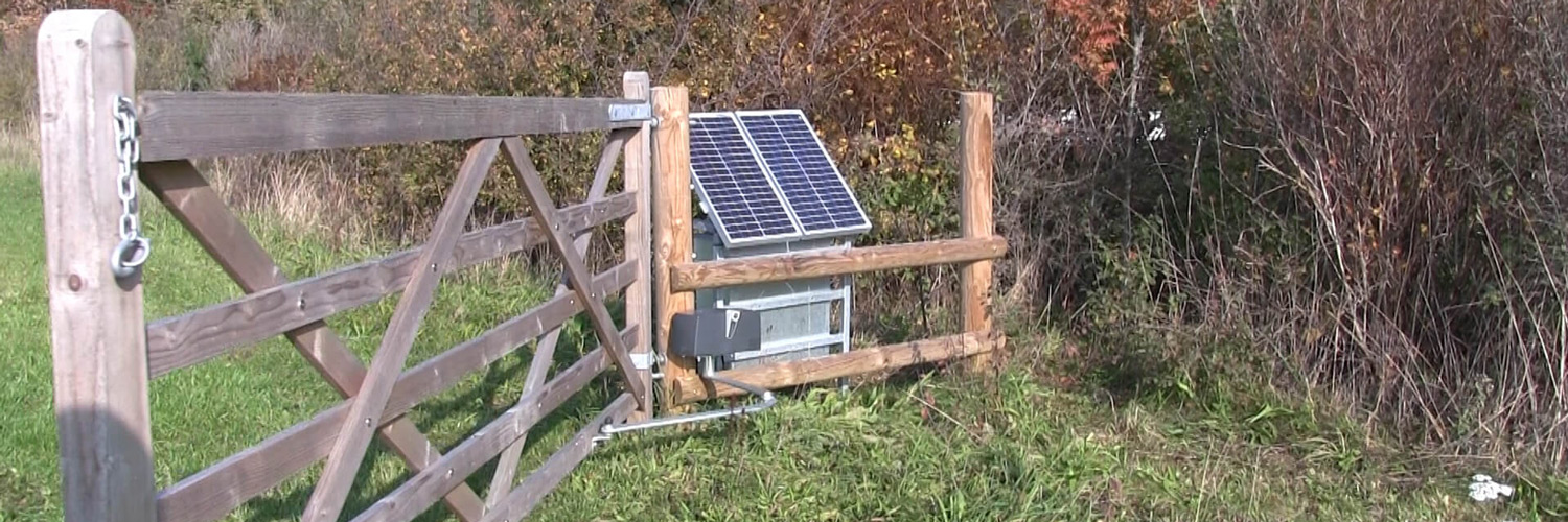 En stor trælåge glider stille op ved hjælp af en soldrevet lågeautomatik | Poda Hegn